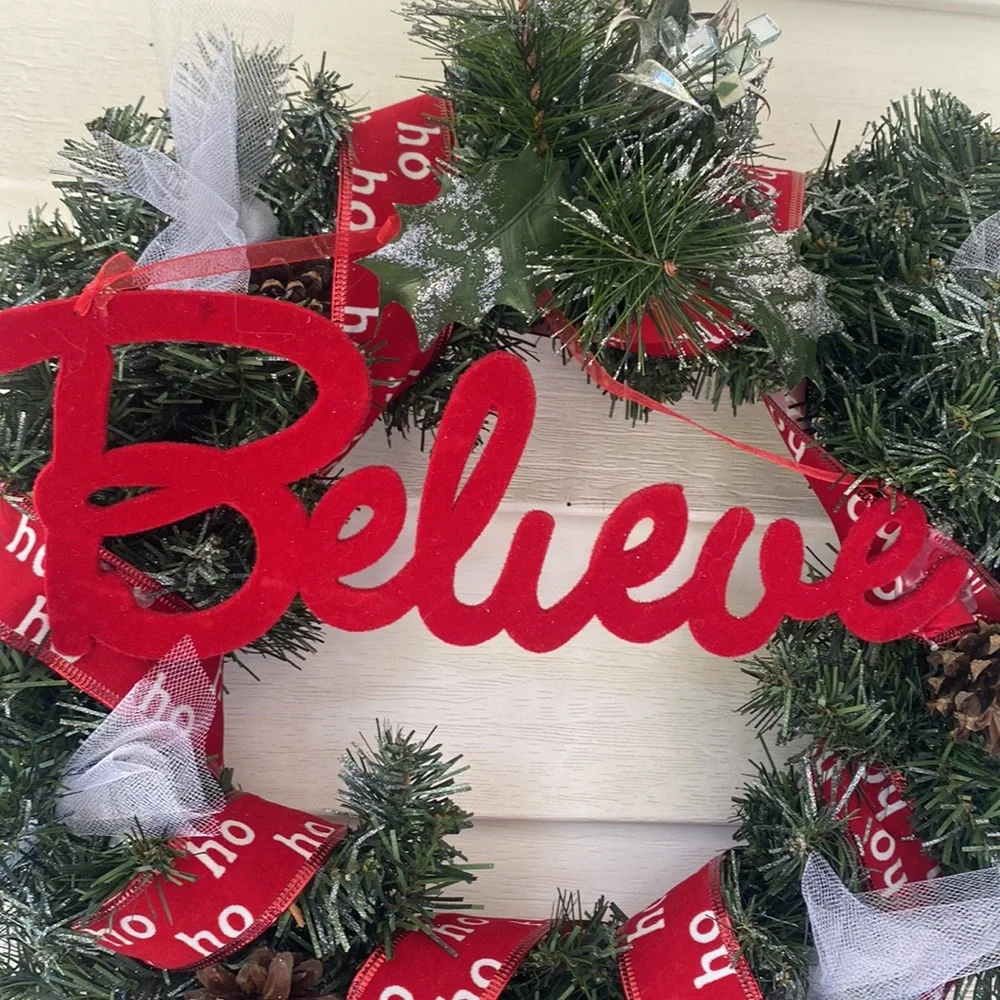 Believe evergreen faux wreath trimmed with the word believe and ho ho ho ribbon